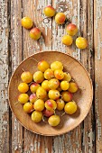 Yellow plums on a wooden plate and next to it