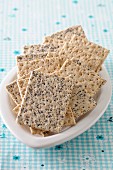 Crackers, some with poppyseeds, in a ceramic bowl