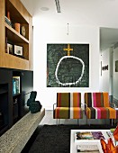Armlehnsessel mit Streifenbezug vor modernem Bild, seitlich Wandschrank im Wohnzimmer