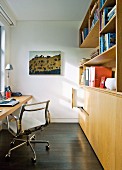 Classic office chair at desk and wooden fitted cupboards in narrow study