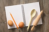 Notizbuch, Küchenutensilien und Eier