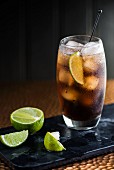 A Cuba Libre with ice cubes and limes