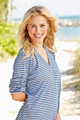 A young blonde woman on a beach wearing a striped t-shirt