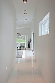 Narrow hallway with white tiled floor leading to living area