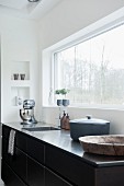 Kitchen counter with stainless steel worksurface below window with garden view