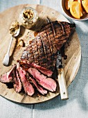 Striploin Steak auf Holzbrett, teilweise in Scheiben geschnitten