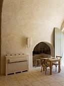 Arched niche and masonry sideboard next to small dining table and chairs in restored Apulian trullo