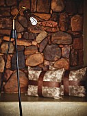 Retro standard lamp with wire lampshade in front of stone wall
