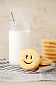 Smiley jam sandwich biscuits with a glass of milk