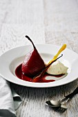 A poached red wine pear with vanilla ice cream