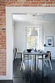 View of dining set through doorway in brick wall with white frame