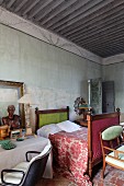 Antique sleigh bed with patterned bedspread, table and retro swivel chair in Mediterranean bedroom