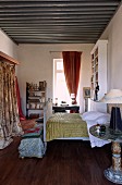 Quilt on antique sleigh bed and wardrobe with patterned curtain in Mediterranean interior