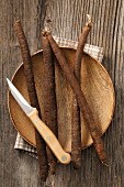 Fresh black salsify on a wooden plate with a knife
