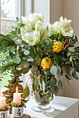 Festive bouquet with white amaryllis and clove-stuffed lemons in glass vase