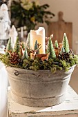 White pillar candle and Christmas decorations arranged in zinc tub
