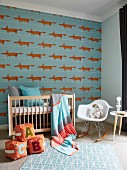 Dog-patterned wallpaper, cot, cushion building blocks on floor and classic rocking chair in nursery
