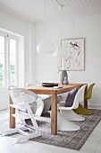 Wooden table and designer chairs in white dining room