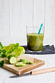 A glass of ginger and cucumber smoothie with a straw