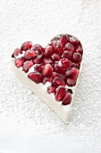 A white chocolate heart with pomegranate seeds in a mold