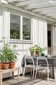 White plastic chairs around set table on terrace outside white wooden house