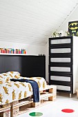 Teenager's attic bedroom with bed on pallets