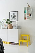 Bright yellow step stool next to sideboard below B-shaped shelving unit