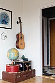Globus auf einem Stapel antiker Koffer, darüber eine Gitarre