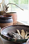 Weathered pieces of wood in ceramic bowl on windowsill