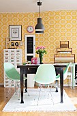 Pastellgrüne Schalenstühle um dunkelbrauen Holztisch in Esszimmer mit gelb-weiss gemusterter Tapete
