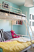 White metal bunk beds with ladder decorated with fairy lights in teenagers' bedroom with pale blue walls