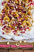 Rosewater pavlova with cream, syrup-soaked figs and pomegranate seeds