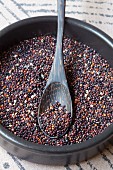 Black quinoa in a bowl with a wooden spoon