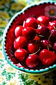 Bright red cherries in a colourful ceramic bowl