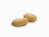 Zwei Erdnüsse ohne Schale vor weißem Hintergrund (Nahaufnahme)