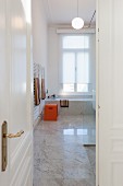 Blick durch offene Tür in modernes Marmorbad von Altbauwohnung
