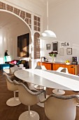 Classic oval table with marble top and matching Tulip armchair with view of lounge area through traditional arched doorway