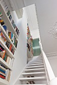 View up staircase lined by floor-to-ceiling bookcases