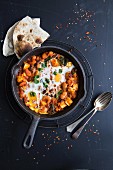 Vegetable curry with fried eggs and unleavened bread (India)