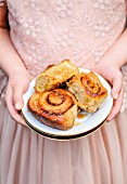 A little girl holding a plate of cinnamon buns