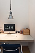 Monitor on desk below retro pendant lamp