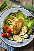 Chicken breast with an orange and honey glaze on a bed of grilled vegetables and lettuce leaves