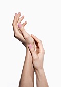 Fraunehände mit rosa lackierten Fingernägeln