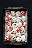 Meringues with strawberry swirls, cardamom, poppy seeds, chopped pistachios and pumpkin seeds