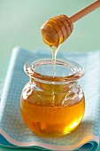 Honey dripping from a honey spoon in a jar