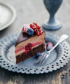 A slice of chocolate mousse cake with rum, raspberries, blueberries and redcurrants