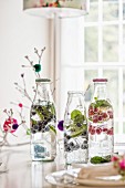 Mineralwasser mit Beeren und Limettenscheiben in Flaschen