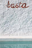 Detail einer weißen Wand mit Schritzug basta