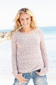 Junge blonde Frau in gestricktem Pulli und Jeans am Meer