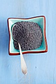 A bowl of poppy seeds with a spoon
